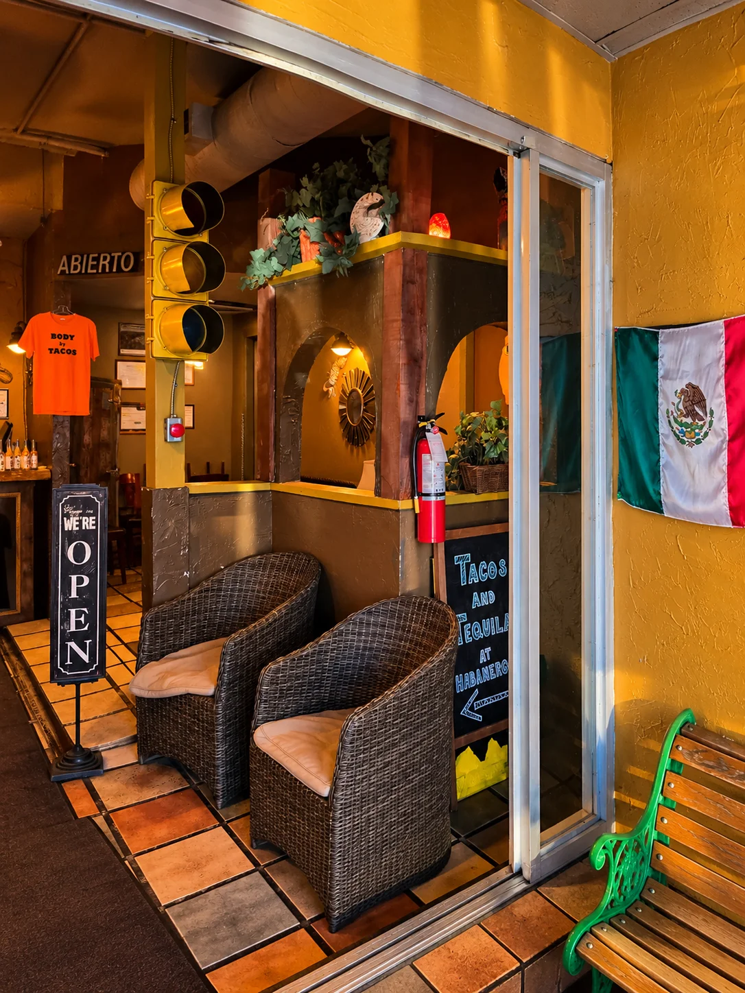 Front entrance of Habaneros Mexican Grill on 48A Street in Leduc, AB with wicker chairs and a Mexican flag